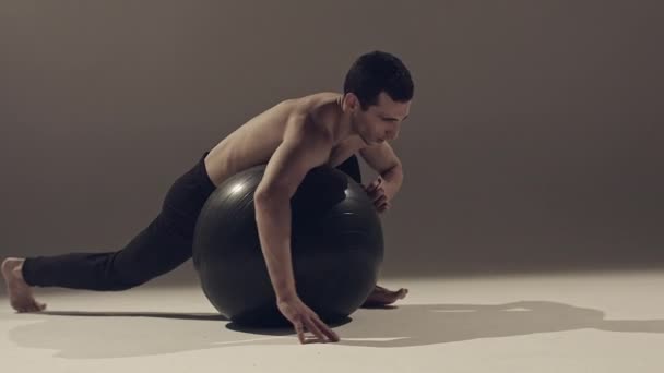 young man dancer making exercises with yoga ball in studio - Materiał filmowy, wideo