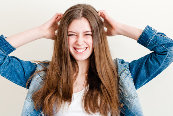 Portrait of a beautiful teen girl happy smiling in jeans with hands on head - Фото, изображение