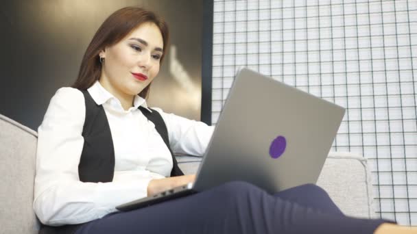 4. Asiatica donna d'affari in ufficio lavora sul divano con computer portatile. Rispondi alla chiamata
.  - Filmati, video