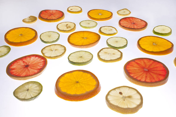recurso gráfico, fatias de citrinos colocadas na superfície translúcida e iluminadas de baixo
 - Foto, Imagem
