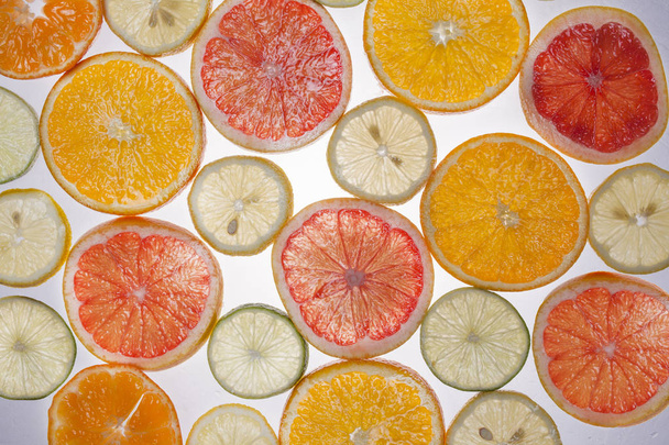 grafische resource, plakjes citrus geplaatst op doorzichtige oppervlak en van onderen verlicht - Foto, afbeelding