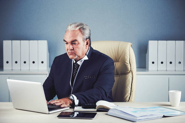 aged business man sitting at office desk table and using laptop  - Foto, imagen