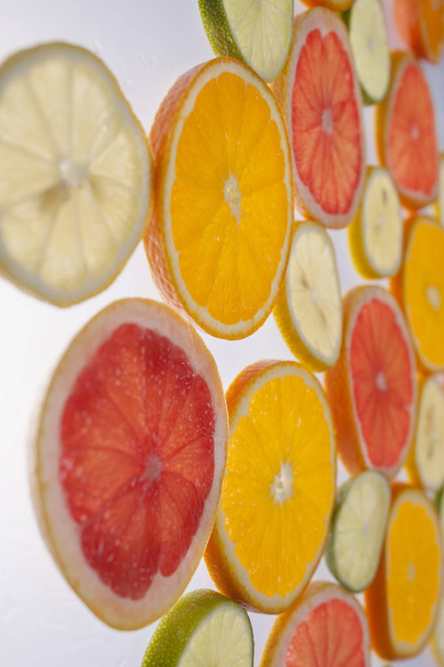 grafische resource, plakjes citrus geplaatst op doorzichtige oppervlak en van onderen verlicht - Foto, afbeelding