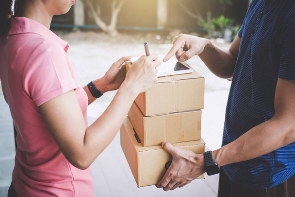 Woman customer appending signature in digital tablet and receiving a cardboard boxes parcel from delivery service courier, Home delivery service and working with service mind. - Foto, Imagem