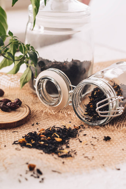 Black tea with natural additives in a glass jar - Foto, afbeelding