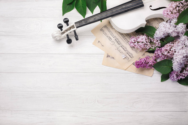 Um buquê de lilases com violino e folha de música em uma mesa de madeira branca. Amor fundo primavera. Top wiev com espaço para o seu texto
. - Foto, Imagem