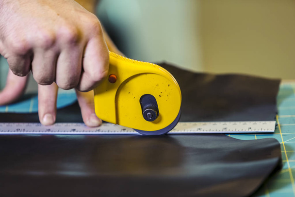 Cutting a piece of leather with a rotary cutter - Foto, immagini