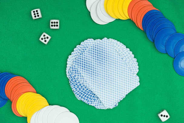 pohled shora zelené pokerového stolu s vícebarevné čipy, hrací karty a kostky - Fotografie, Obrázek