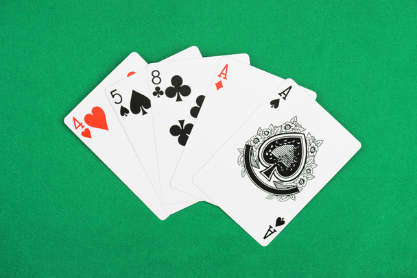 вид на зеленый покерный стол и развернутые игральные карты с различными мастями
 - Фото, изображение