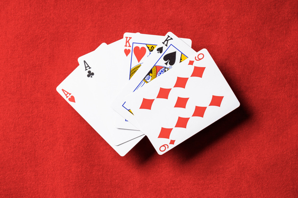 pohled shora červené pokerového stolu a nepřeložené hrací karty v různých barvách - Fotografie, Obrázek