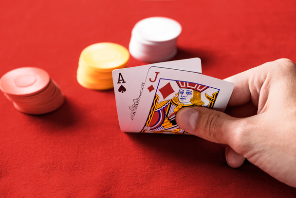 επιλεκτική εστίαση του ανθρώπου που κρατώντας παίζοντας κάρτες με τσιπ σε φόντο - Φωτογραφία, εικόνα