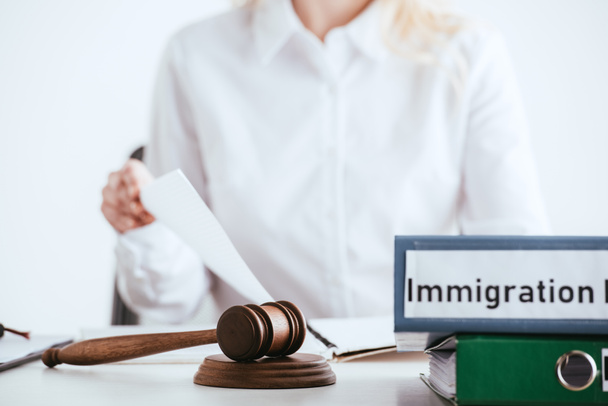 Selektivní fokus kladívkem u složek s imigrační zákon nápis s ženou na izolované na bílém pozadí - Fotografie, Obrázek