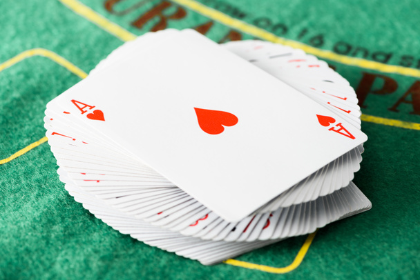 selective focus of playing card with hearts suit on deck at green poker table  - Foto, afbeelding