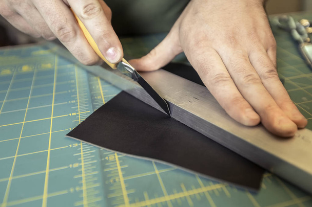 Cutting leather with a handheld straight blade - Foto, imagen