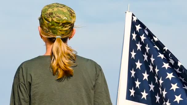 Voják žena stojan s americkou vlajkou. Zadní pohled, pomalý pohyb - Záběry, video