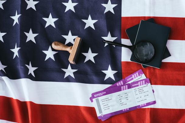 Κάτοψη των διαβατηρίων και Μεγεθυντικός φακός κοντά εισιτήρια και την αμερικανική σημαία  - Φωτογραφία, εικόνα