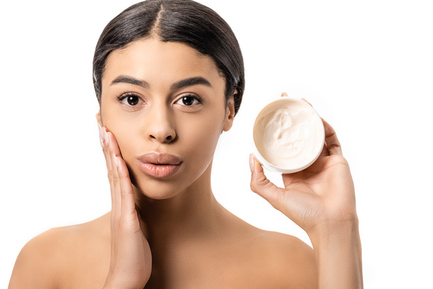 attractive young african american woman holding container with cream and touching face isolated on white - 写真・画像