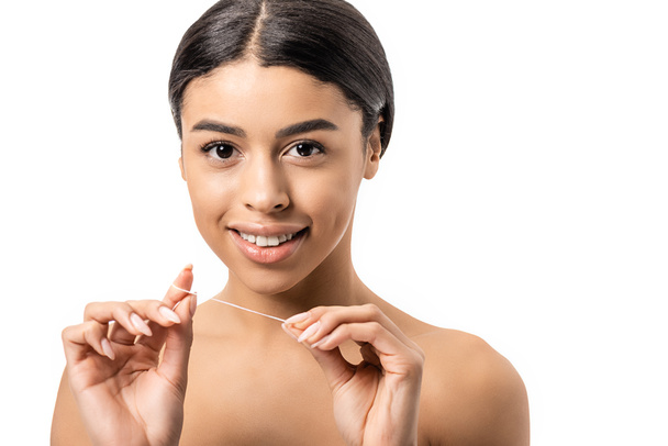 beautiful young naked african american woman holding dental floss and smiling at camera isolated on white - Foto, Imagem