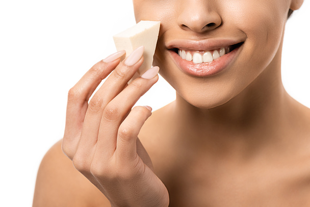 close-up partial view of smiling young african american woman holding makeup sponge isolated on white - Photo, Image