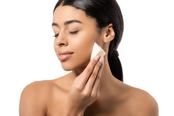 beautiful naked african american girl with closed eyes holding makeup sponge isolated on white - Photo, Image