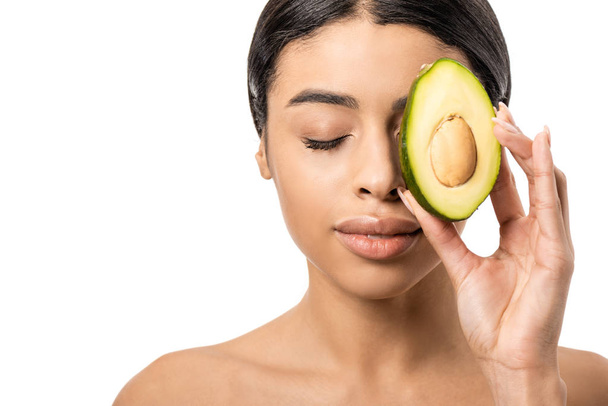 beautiful young african american woman holding half of avocado near face isolated on white - Zdjęcie, obraz