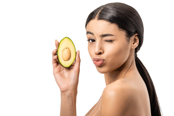 beautiful naked african american woman holding avocado and winking at camera isolated on white  - Foto, Bild