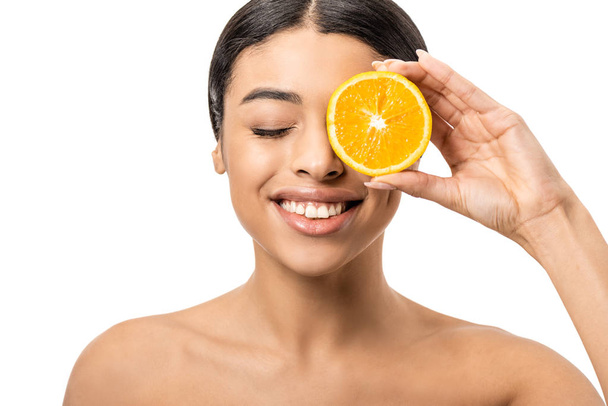 beautiful smiling african american girl holding slice of orange near face isolated on white - Foto, Imagem