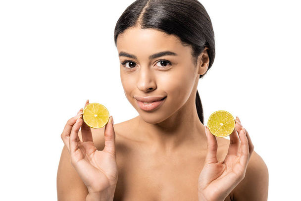 attractive naked african american girl holding halves of lime and smiling at camera isolated on white - Photo, Image