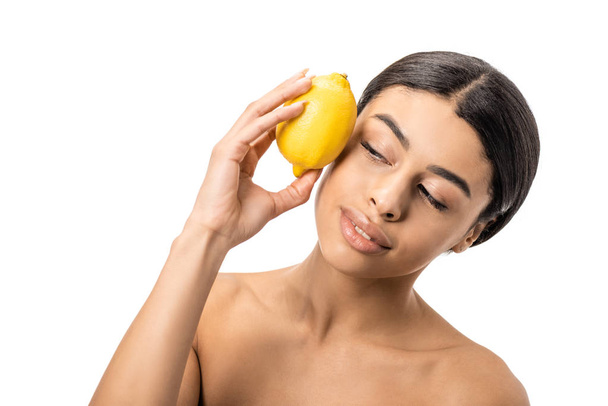 beautiful naked african american girl holding fresh lemon near face isolated on white  - Fotografie, Obrázek