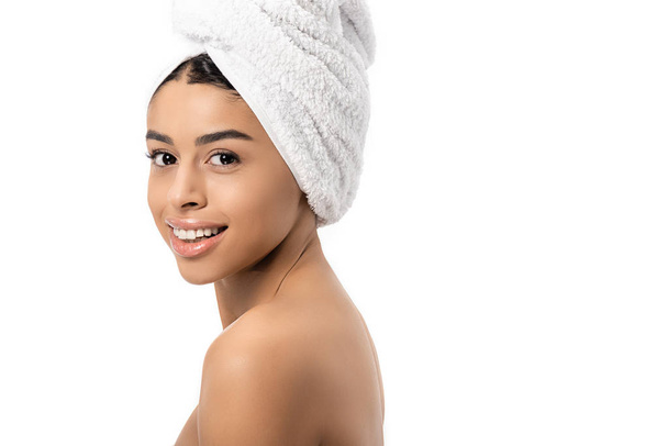 vista lateral de hermosa mujer afroamericana desnuda con toalla en la cabeza sonriendo a la cámara aislada en blanco
 - Foto, imagen