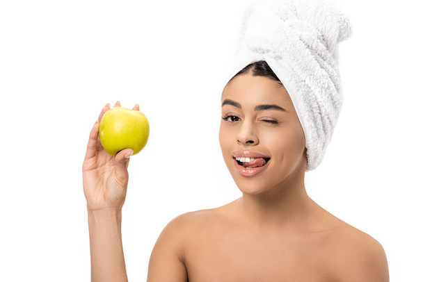 heureuse jeune femme afro-américaine avec serviette sur la tête tenant pomme fraîche et clin d'oeil à la caméra isolée sur blanc
 - Photo, image