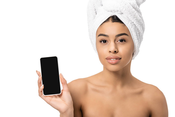 attractive african american girl with towel on head holding smartphone with blank screen and looking at camera isolated on white - Foto, Imagem
