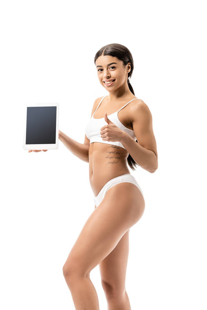 feliz jovem afro-americana em roupa interior segurando tablet digital com tela em branco e mostrando polegar isolado no branco
 - Foto, Imagem
