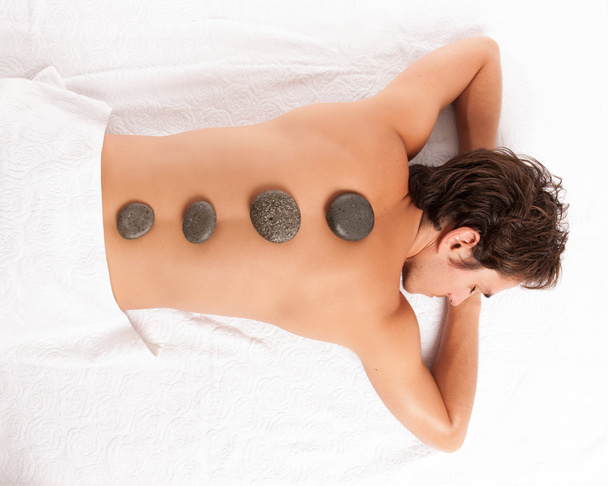 junger Mann auf einem Wellnessbereich bekommt eine Hot-Stone-Massage. - Foto, Bild