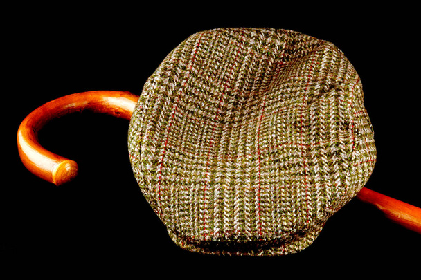Tweed cap and walking stick isolated on a black background - Photo, Image