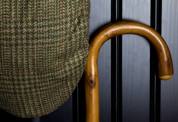 Bastón de caminar y gorra de tweed colgando en la puerta del armario negro
 - Foto, Imagen