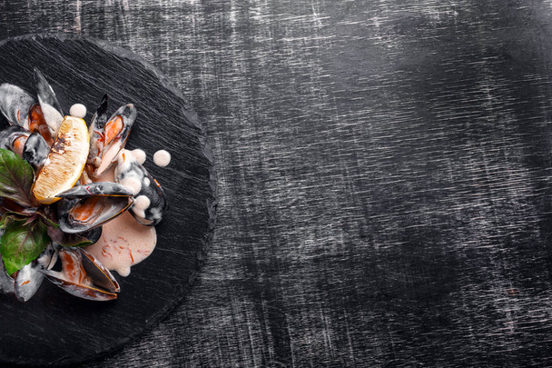 Limon ve fesleğen bir taş ve kara tahta üzerinde krema soslu deniz mahsulleri midye. Metin alanı olan üstten görünüm. - Fotoğraf, Görsel