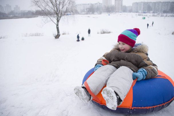 Sledding.Happy dziecko na wakacje. Zimowe zabawy i gry. Mały chłopiec cieszyć jazdą saniami. Dzieci bawią się na zewnątrz w śniegu. Sanki dla dzieci w górach Alpach w zimie - Zdjęcie, obraz