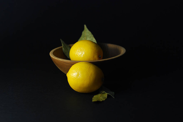 λεμόνι φρούτων σε μαύρο φόντο σε ένα πιάτο με φυσικά υλικά - Φωτογραφία, εικόνα