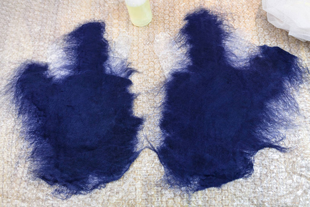 taller de fabricación de guantes de lana de oveja Merino azul utilizando proceso de fieltrado húmedo primera capa humedecida de fibras en el patrón de corte de guantes
 - Foto, imagen
