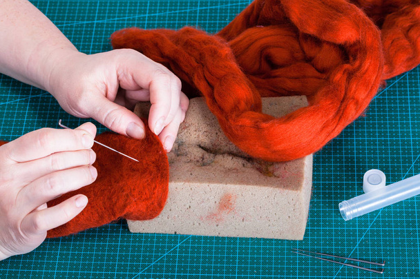master class of repairing fleece glove using Needle felting process - above view of craftsman mixes fibers in felt with felting needle - Photo, Image
