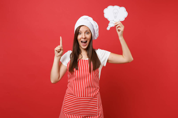 Dona de casa cozinheiro chef ou padeiro em avental listrado branco t-shirt toque chefs chapéu isolado no fundo da parede vermelha. Mulher dona de casa divertida segurar nuvem com ideia lâmpada. Mock up conceito de espaço de cópia
 - Foto, Imagem