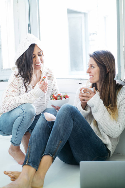 Two women eating fruit and drinking tea at home - Valokuva, kuva