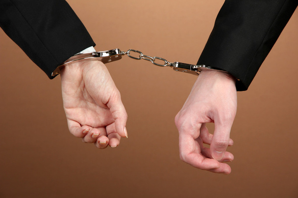 Man and woman hands and breaking handcuffs on color background - Foto, afbeelding
