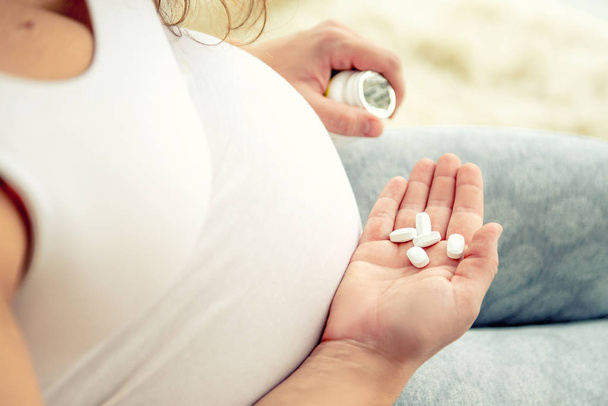Closeup of pregnant womans hand with pills. - Foto, Imagem