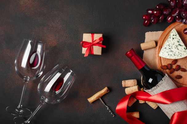 Flasche Wein, Geschenkkarton, rote Trauben, Blauschimmelkäse, Mandeln, Korkenzieher, Seil und Korken, auf rostigem Hintergrund von oben - Foto, Bild
