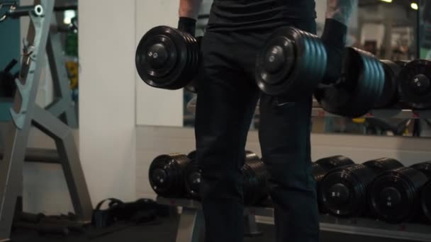 Man doing lift-ups, holding heavy dumbbells in hands - Materiał filmowy, wideo