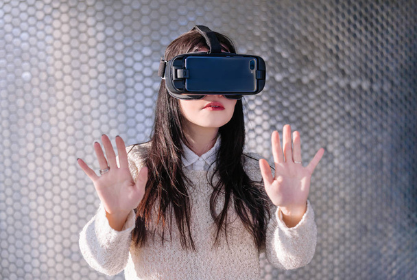 Een jong meisje met een headset op het eerste gezicht voldoet aan nieuwe technologieën. Vrouw met behulp van virtual reality headset. - Foto, afbeelding