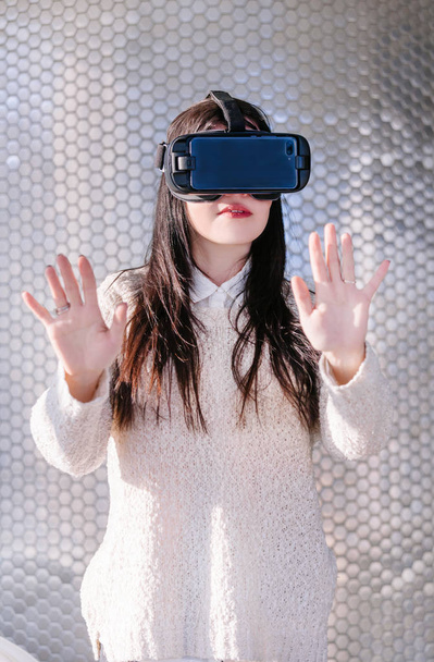 ein junges Mädchen mit einem Headset im Gesicht trifft auf neue Technologien. Frau mit Virtual-Reality-Headset. - Foto, Bild