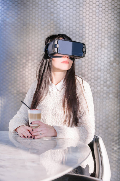 Une jeune fille avec un casque sur le visage rencontre les nouvelles technologies. Femme utilisant casque de réalité virtuelle
. - Photo, image